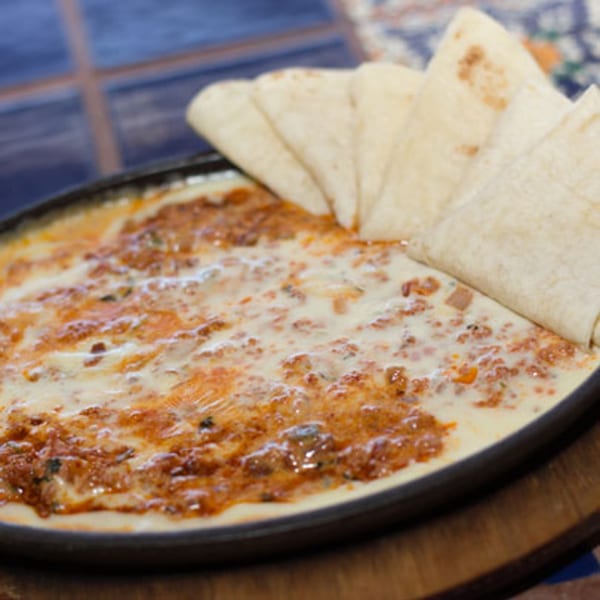 Sizzling skillet of melted cheese and chorizo, served with warm tortillas at Los Cocos Mexican Restaurant.