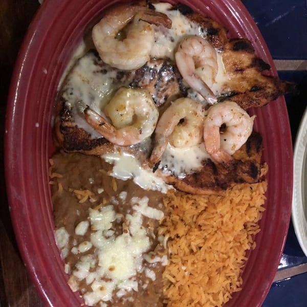 Grilled chicken and shrimp topped with white sauce, served with refried beans and Mexican rice.