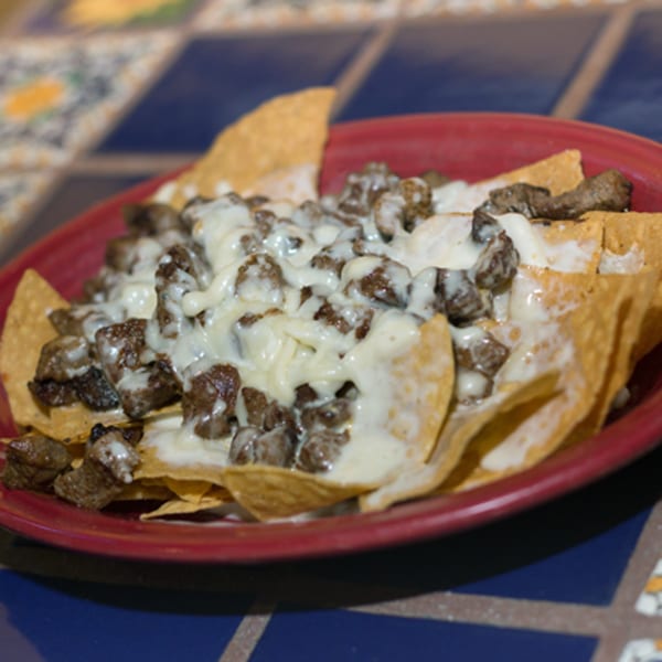 Los Cocos Mexican Restaurant's nachos with steak and melted white cheese on a red plate.