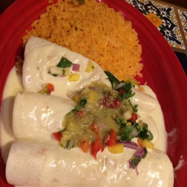 Three cheesy enchiladas topped with salsa verde and pico de gallo, served with Mexican rice.