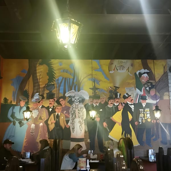 A vibrant mural depicting a Day of the Dead celebration with people and a skeleton figure.
