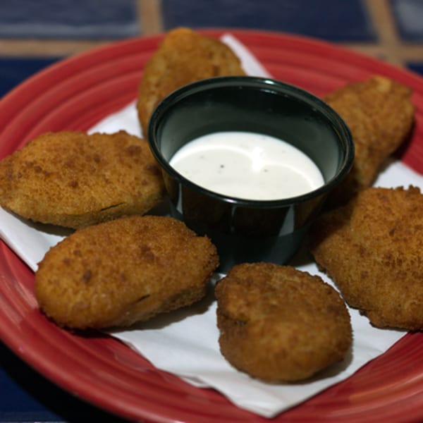 Golden-brown fried appetizers and a small cup of white dipping sauce on a red plate.